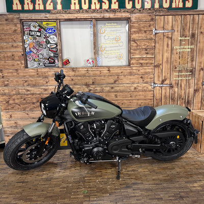 Motorcycle parked inside a building with wooden walls and a sign above.
