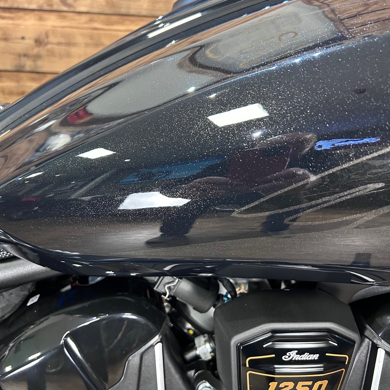 Close-up of a black motorcycle with 'Indian' branding on a wooden background