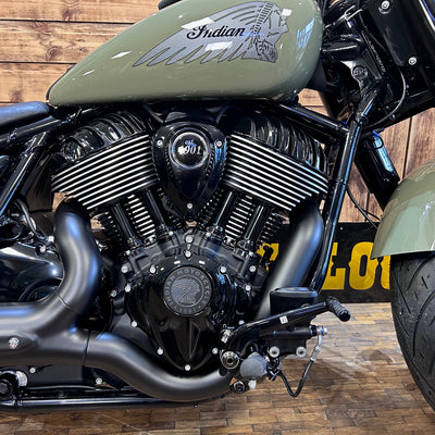 Close-up of a motorcycle engine with 'Indian' branding on a wooden floor.