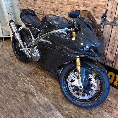 Black sports motorcycle on a wooden floor with a wooden wall background