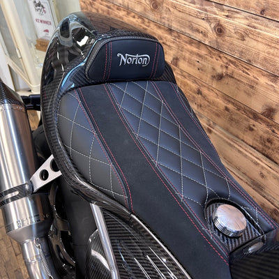 Motorcycle seat with 'Norton' branding against a wooden background