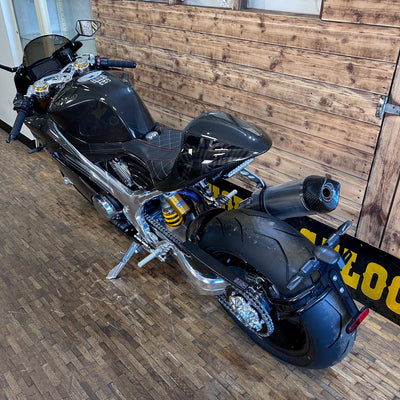 Black motorcycle parked indoors against a wooden wall.