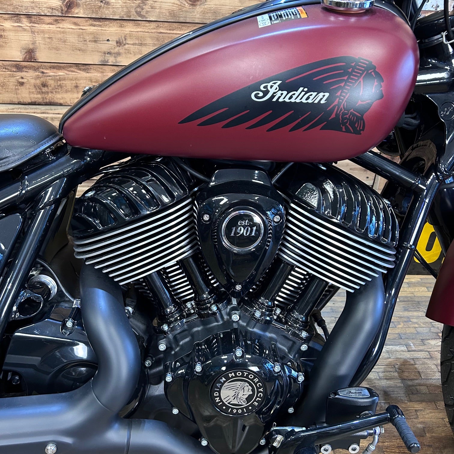 Close-up of an Indian motorcycle engine with red fuel tank against a wooden background