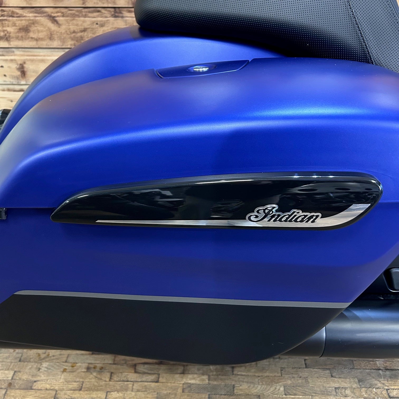 Blue motorcycle with 'Indian' logo on a wooden floor