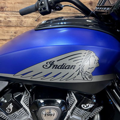Close-up of a blue Indian motorcycle with logo and 'Est. 1901' on a wooden background