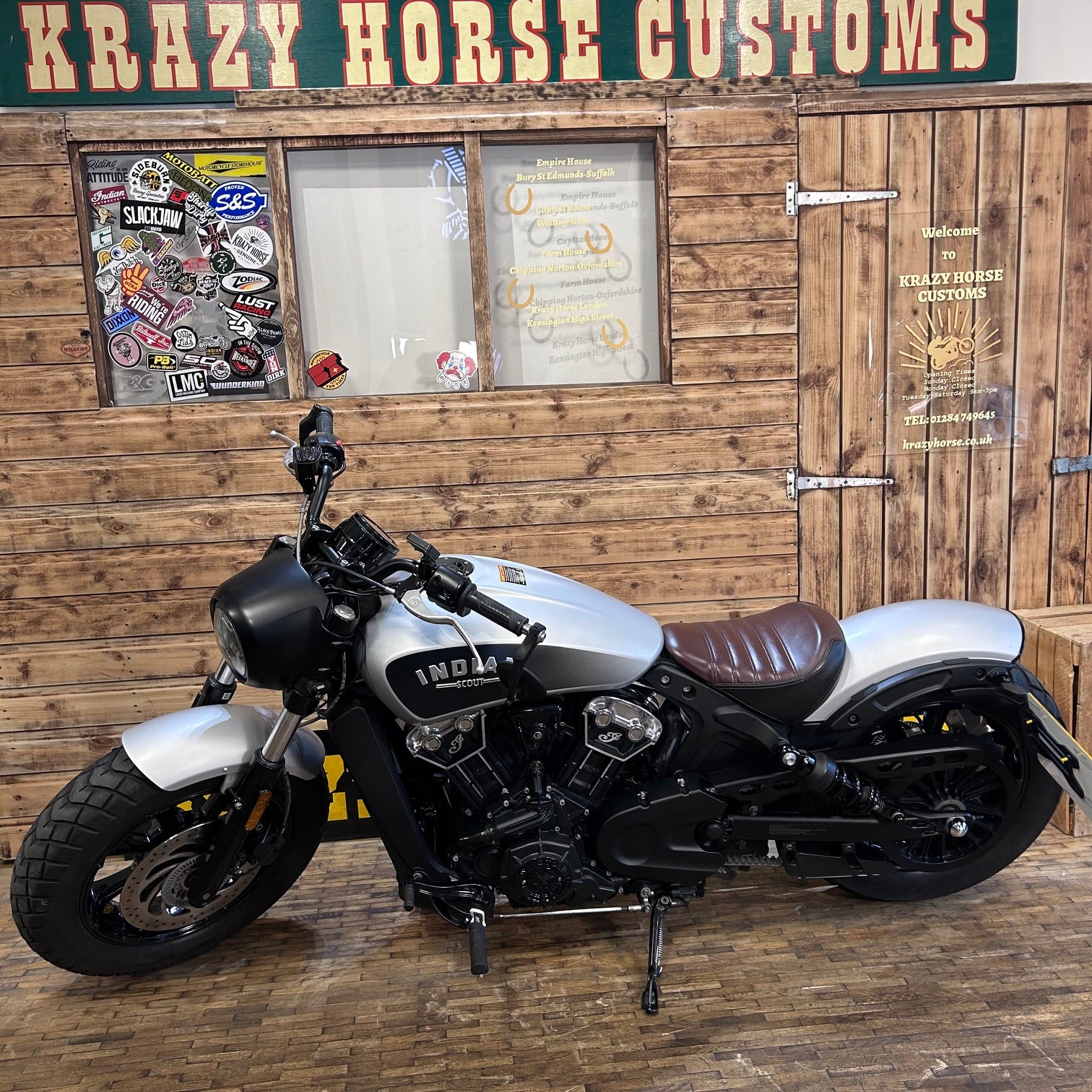 Motorcycle in front of a wooden wall with 'Krazy Horse Customs' sign