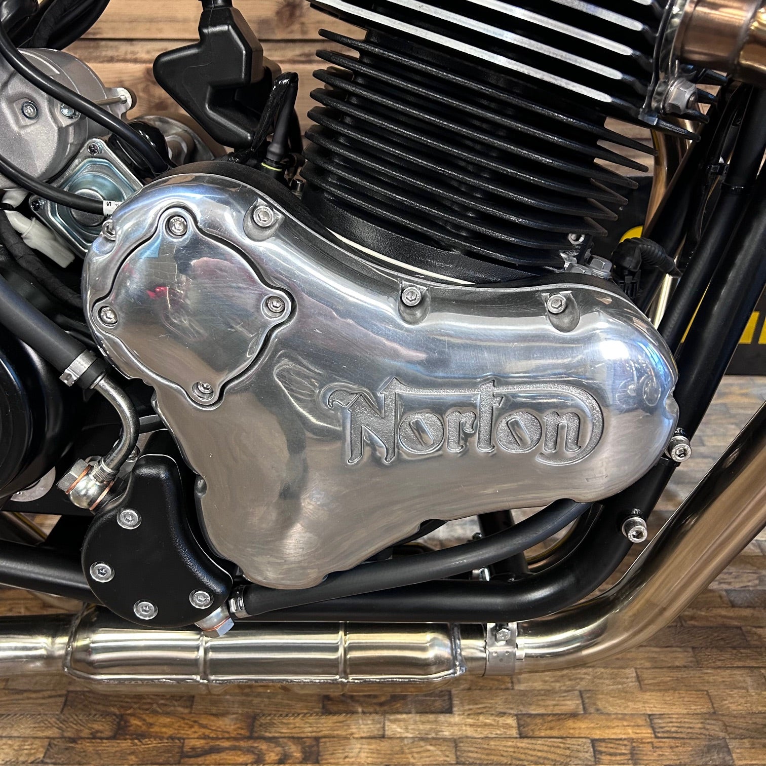 Close-up of a Norton motorcycle engine on a wooden floor.