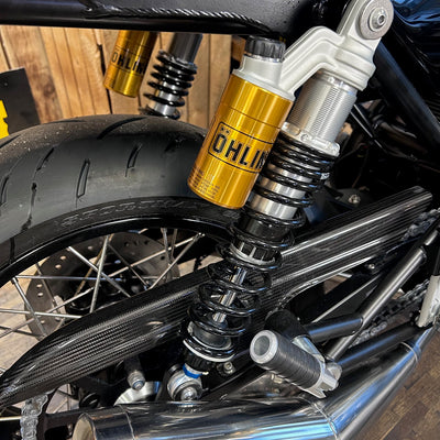 Close-up of motorcycle suspension with Öhlins shock absorber on a wooden background