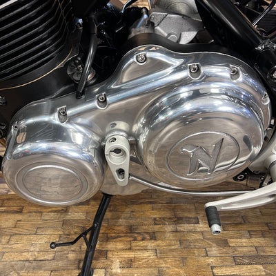 Close-up of a motorcycle engine with a brand logo on a wooden floor.