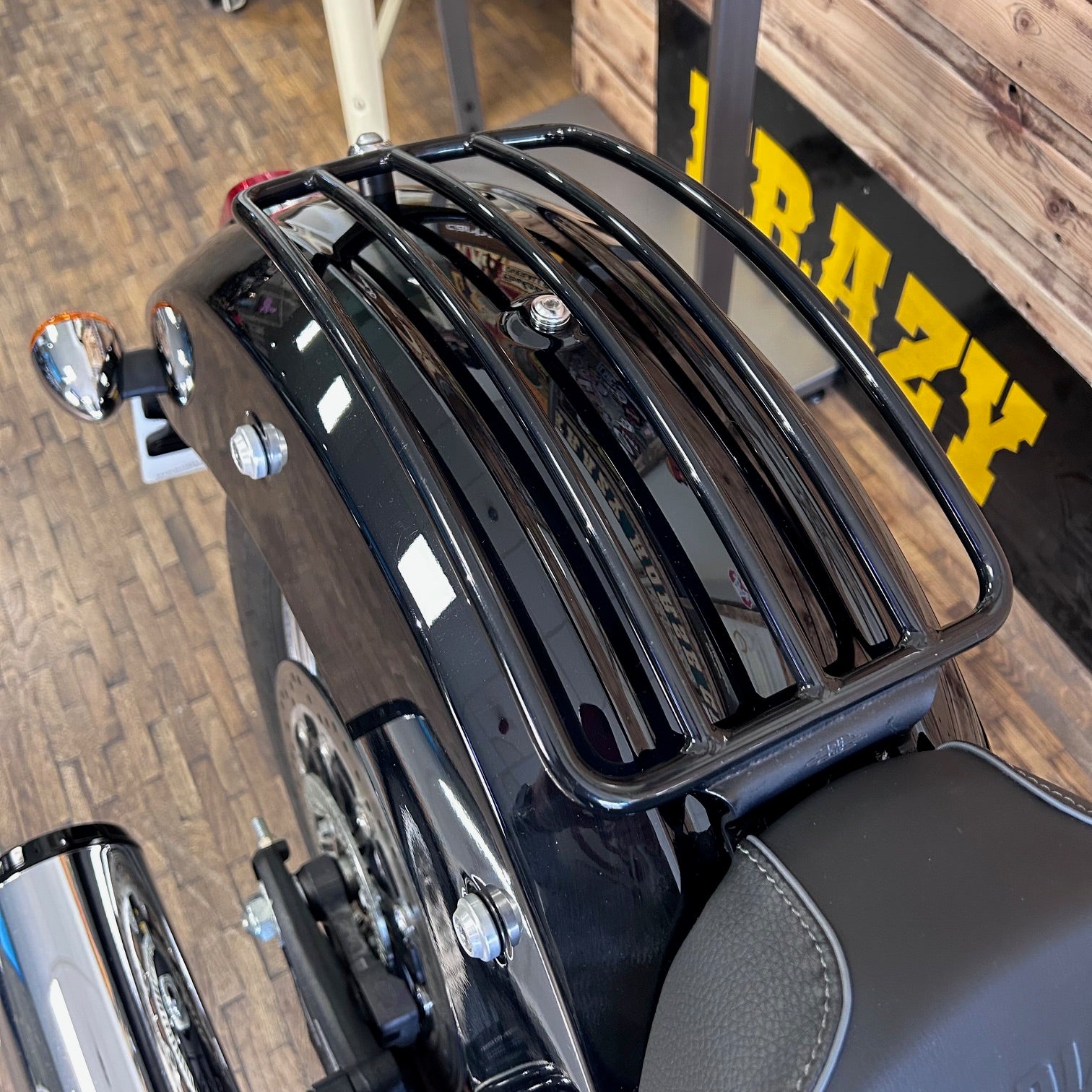 Black motorcycle luggage rack on a vehicle with 'RAZY' branding in the background.