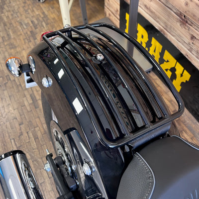 Black motorcycle luggage rack on a vehicle with 'RAZY' branding in the background.