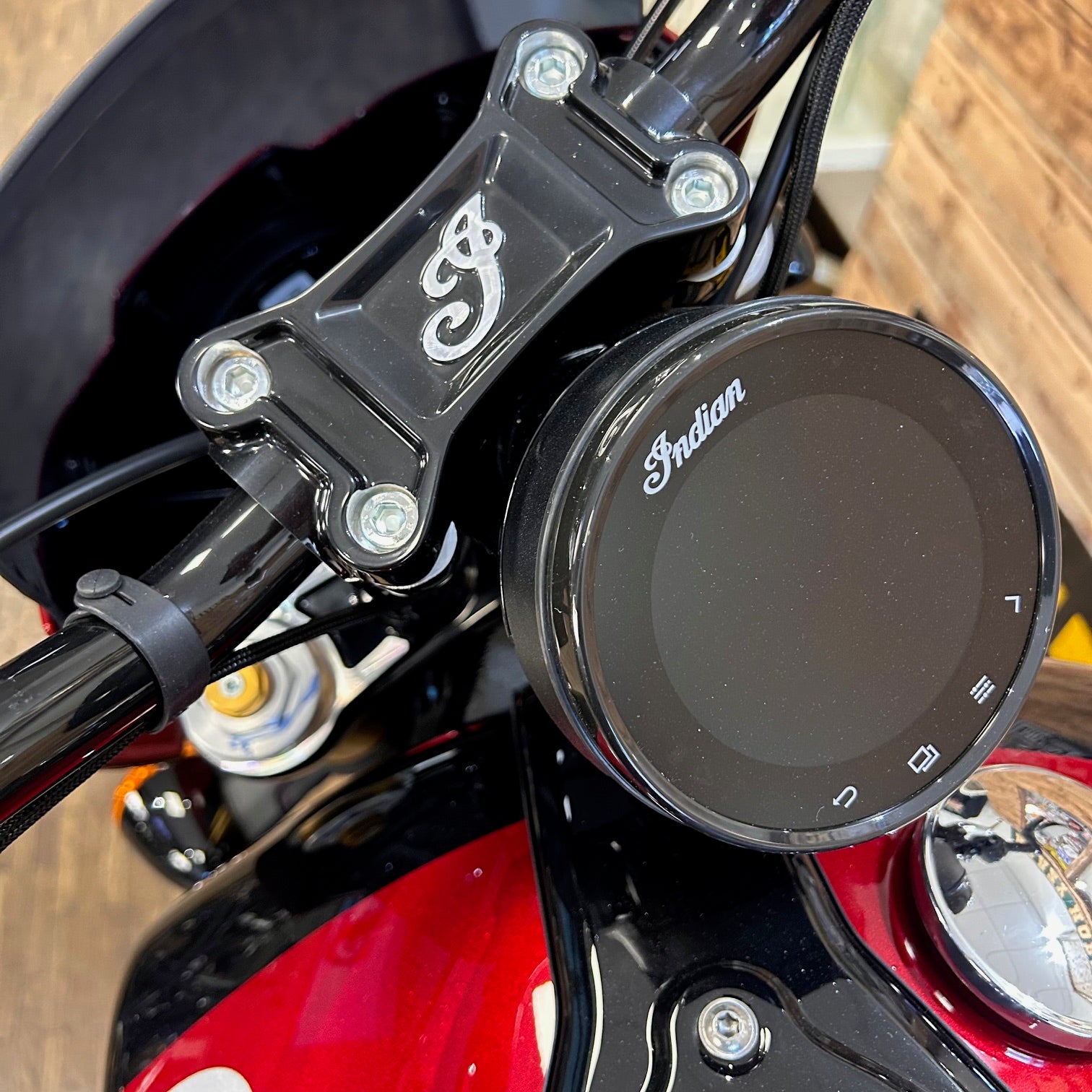 Close-up of a motorcycle handlebar with 'Indian' branding on a wooden surface.