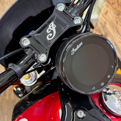 Close-up of a motorcycle handlebar with 'Indian' branding on a wooden surface.