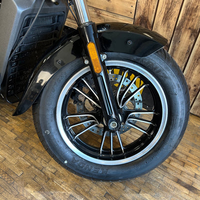 Close-up of a motorcycle wheel with a wooden floor background