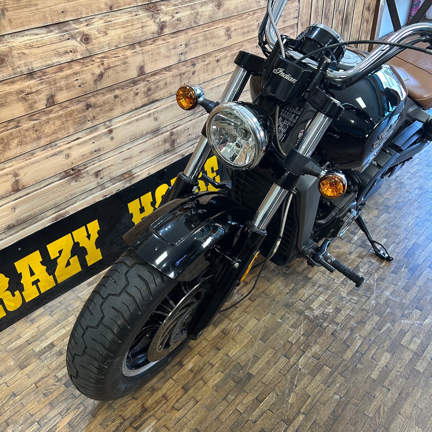 Black motorcycle on a wooden floor with a wooden wall in the background