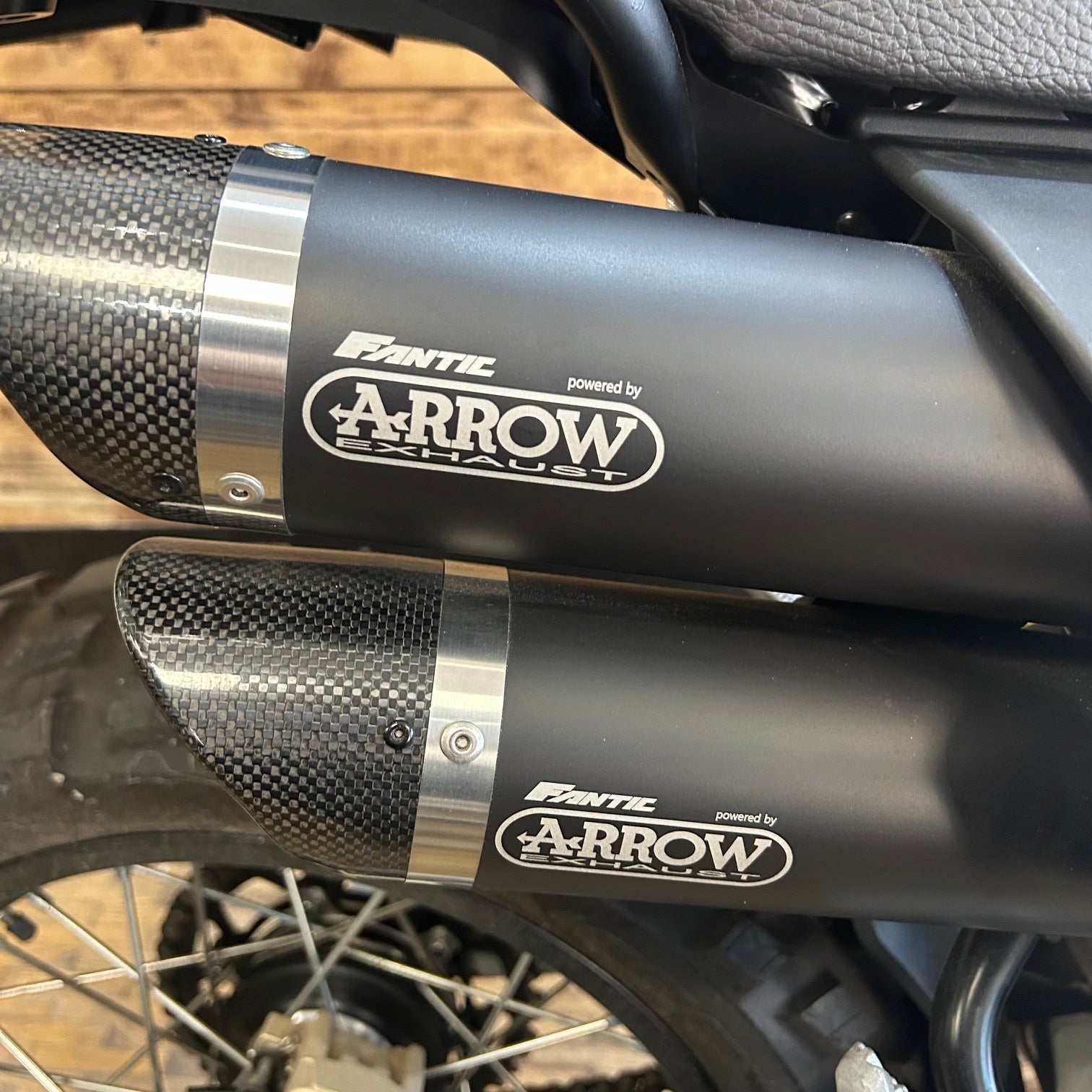 Motorcycle exhaust with 'Fantec' and 'Arrow Exhaust' branding on a blurred background.