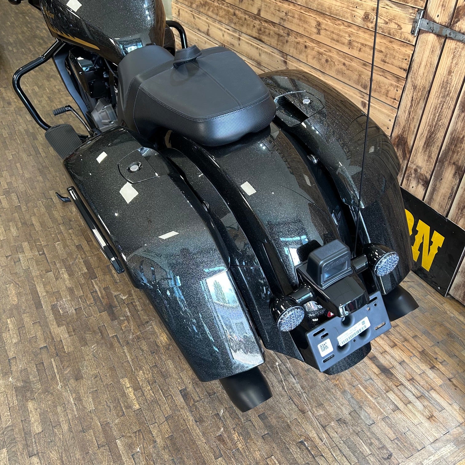 Black motorcycle parked indoors on a wooden floor