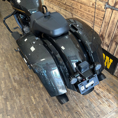 Black motorcycle parked indoors on a wooden floor