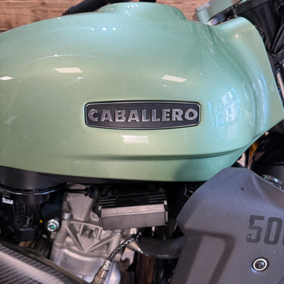 Close-up of a green motorcycle with 'Caballero' branding on a blurred background