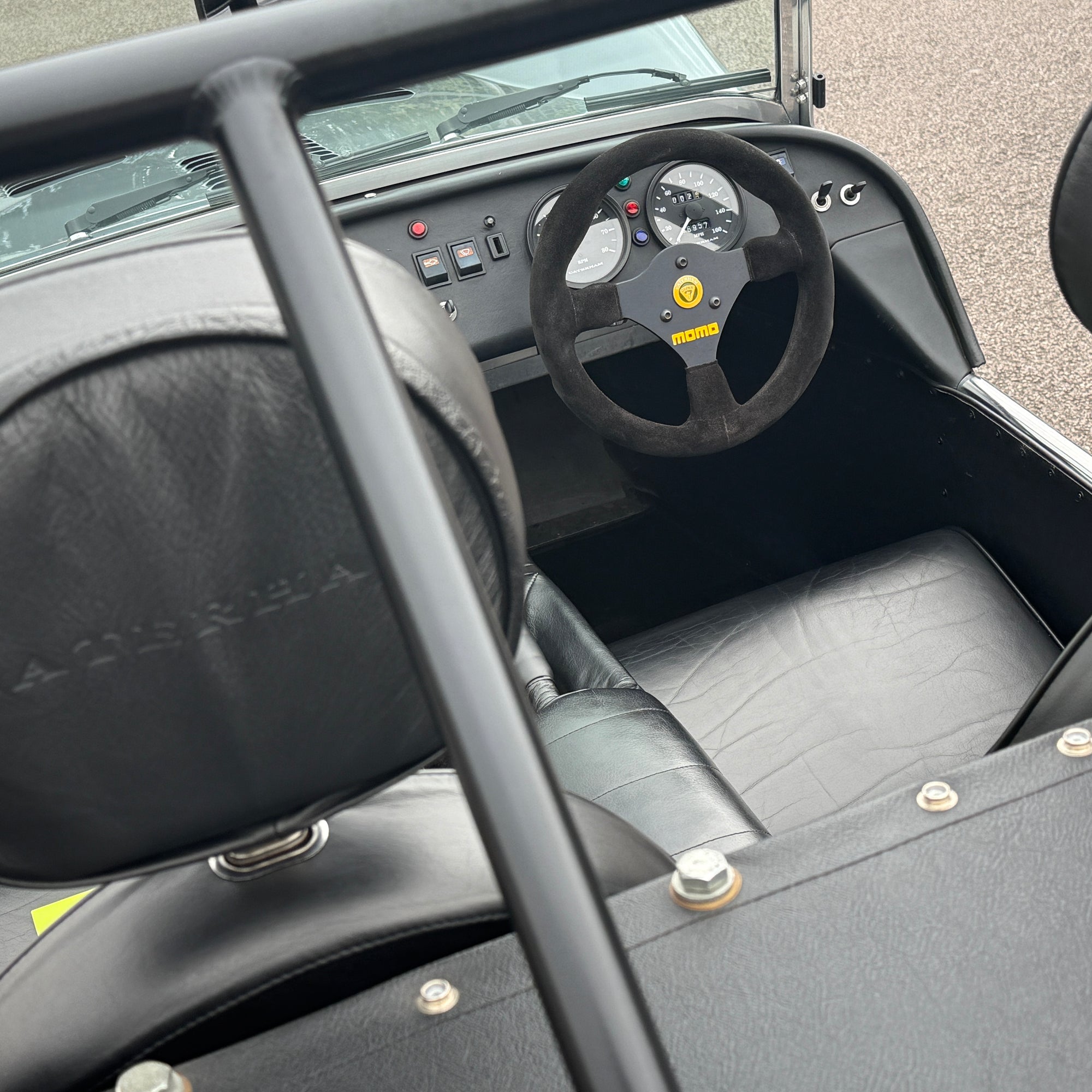 Close-up of a car interior with steering wheel and dashboard, featuring the Maserati logo.