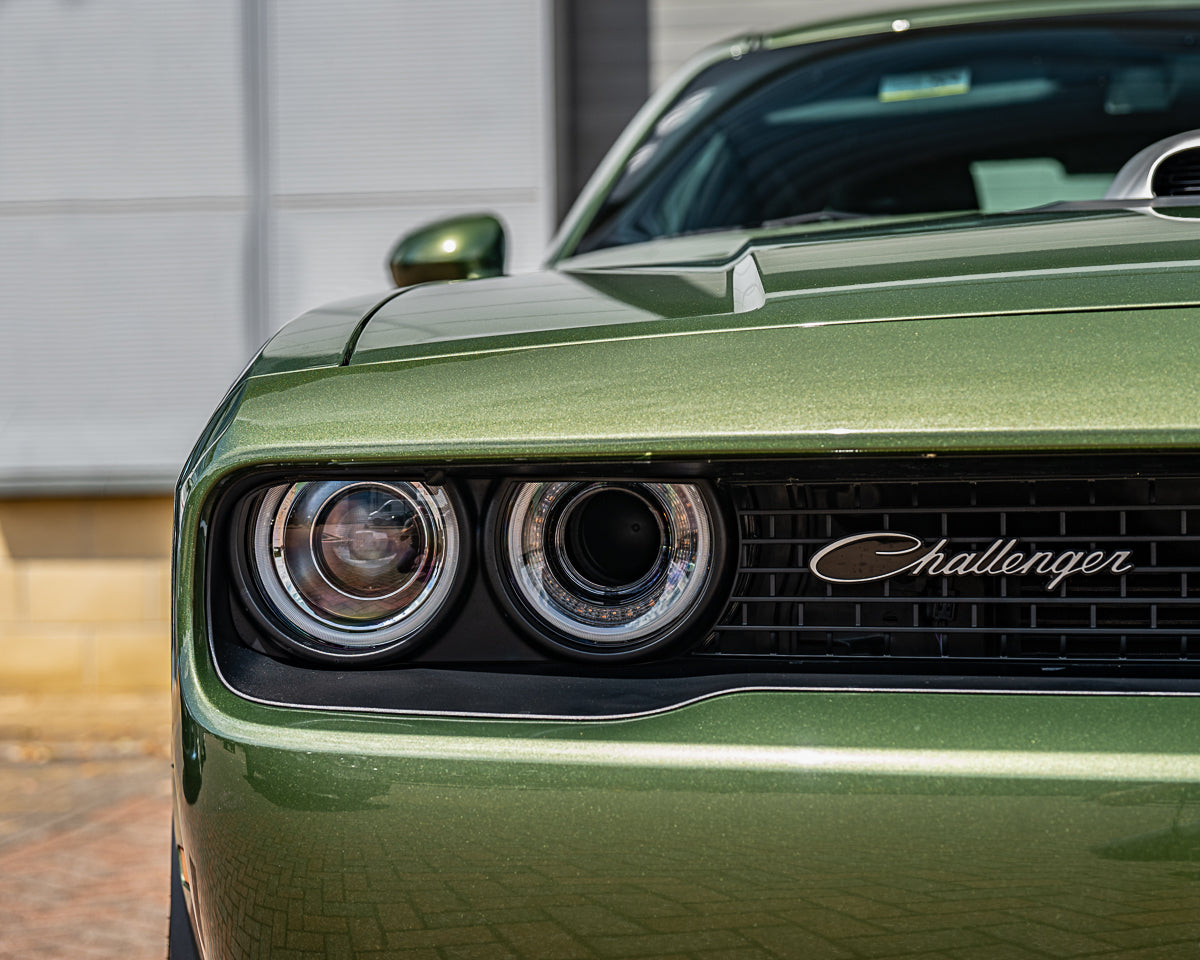 Close-up of a green Dodge Challenger car front with 'Challenger' branding.