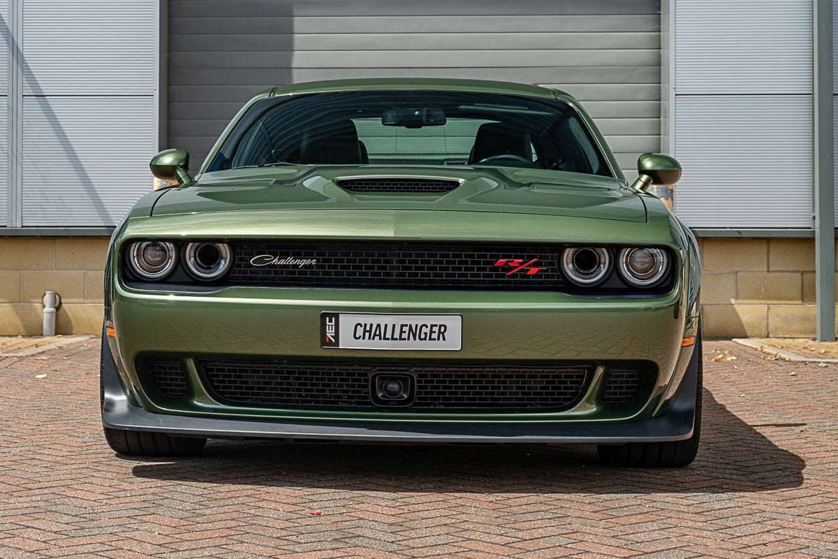Green Dodge Challenger parked in front of a building