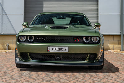 Green Dodge Challenger parked in front of a building