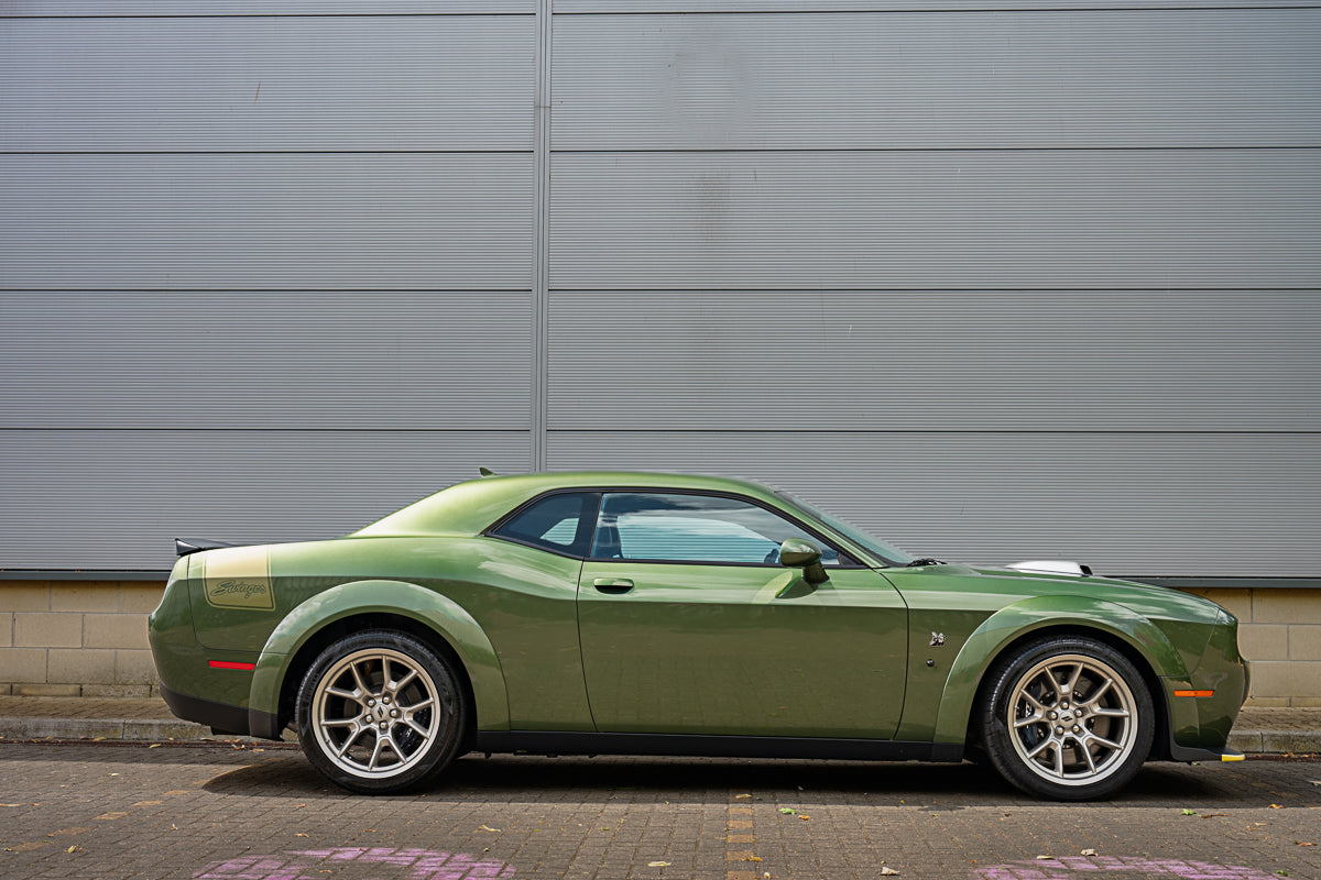 Green sports car parked in front of a gray building