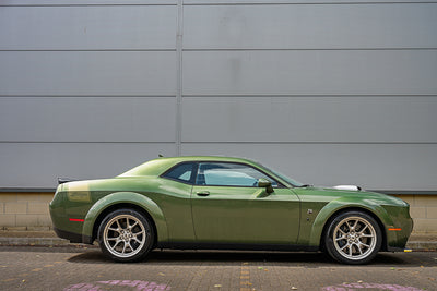 Green sports car parked in front of a gray building