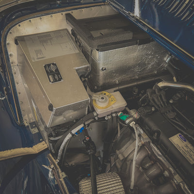 Close-up of vehicle engine compartment with battery and electrical components.
