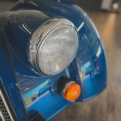 Close-up of a blue vehicle's headlight and turn signal.