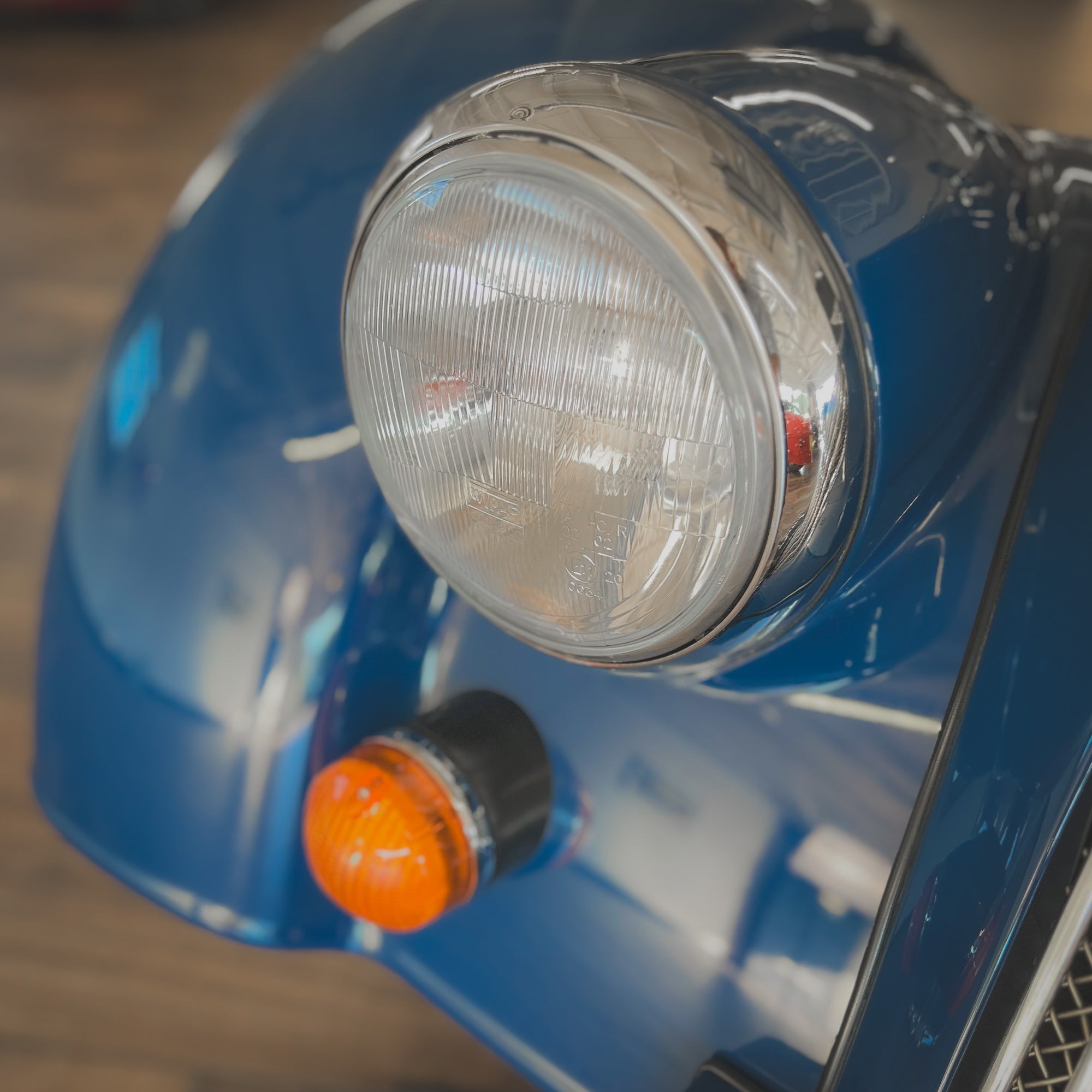 Close-up of a blue vehicle's headlight and turn signal.