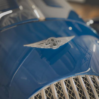 Close-up of a blue car with a visible brand logo on the hood.