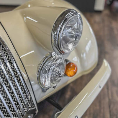 Close-up of a vintage car's front lights and grille.