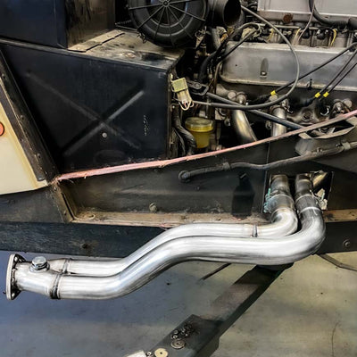 Close-up of a vehicle engine with a metallic exhaust pipe.