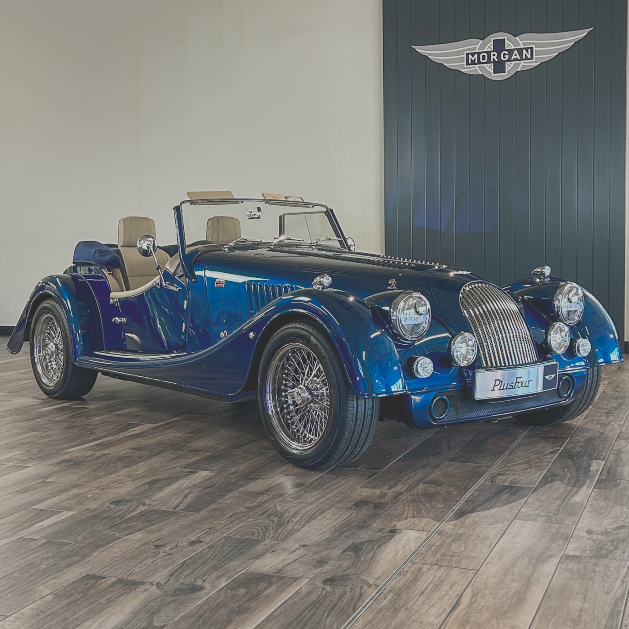 Blue vintage car on a wooden floor with a branded wall in the background