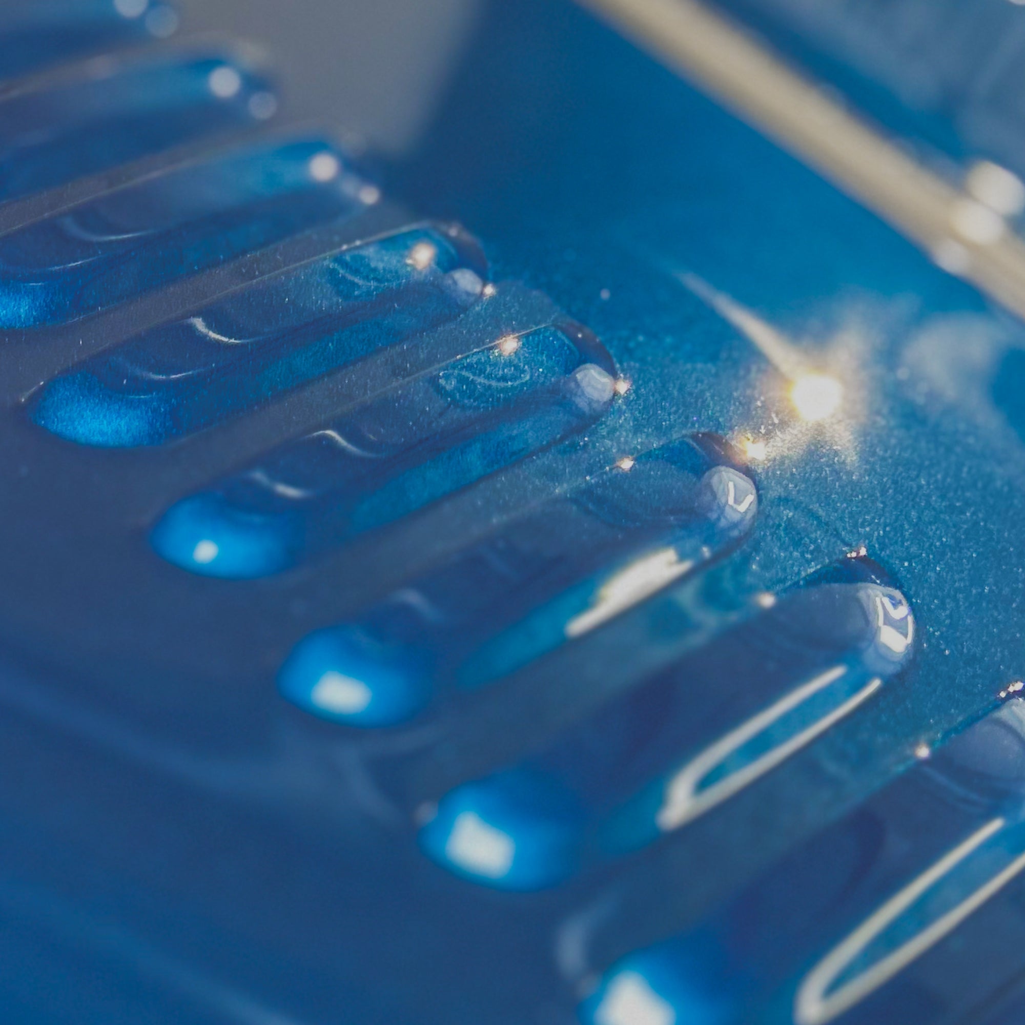 Close-up of a blue plastic comb with water droplets on it.