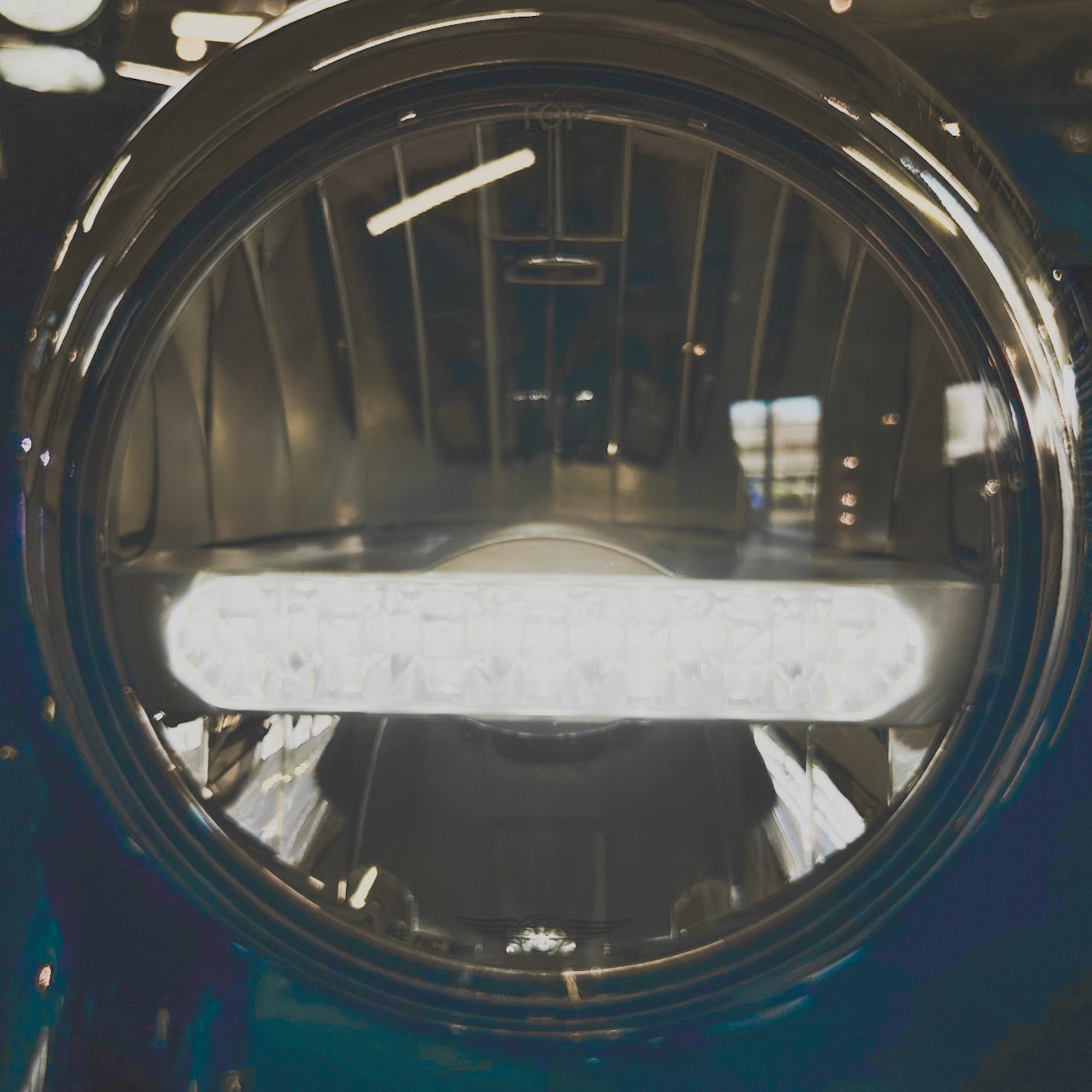 Close-up of a round headlight with a metallic finish on a vehicle.