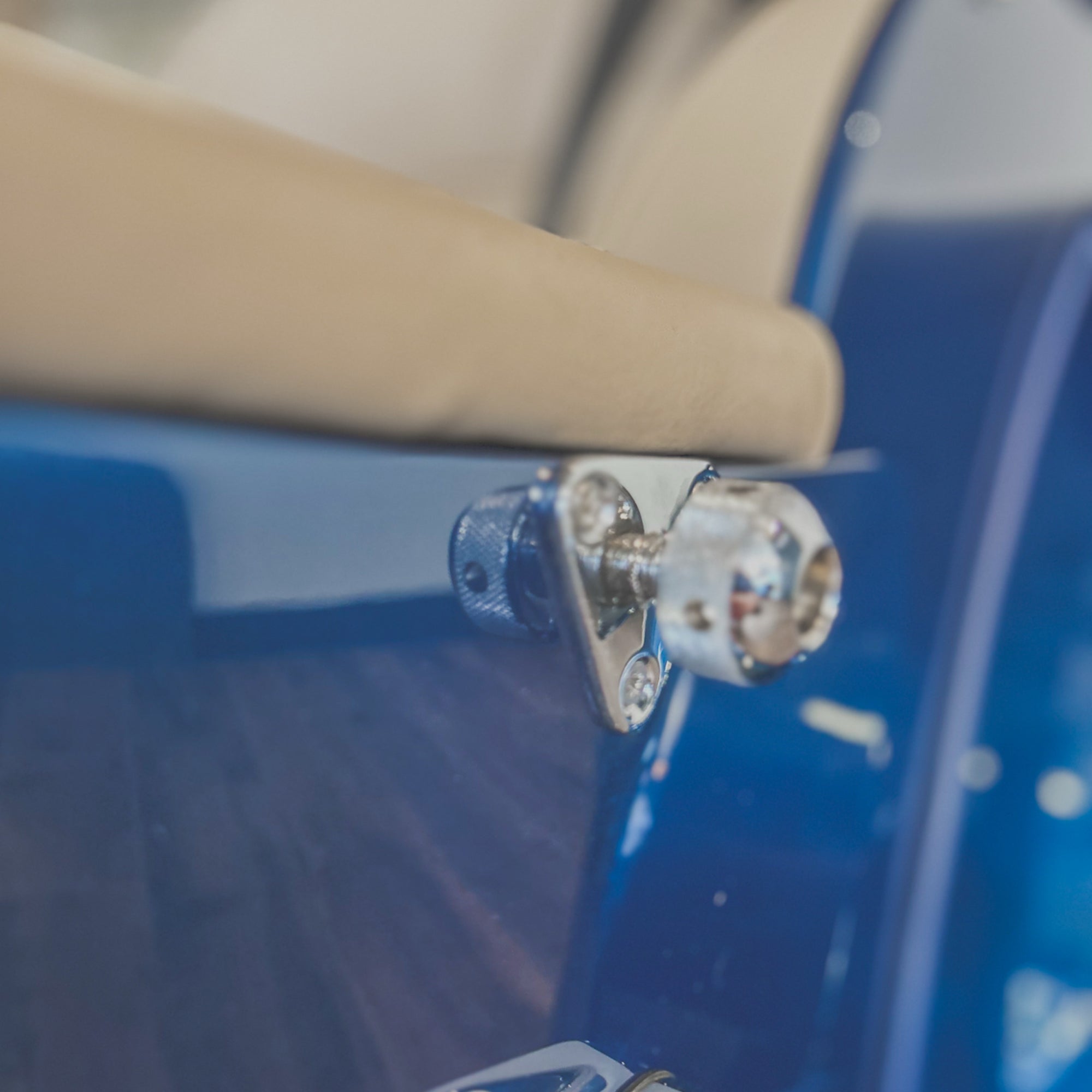 Close-up of a car door handle on a blue car with beige interior.