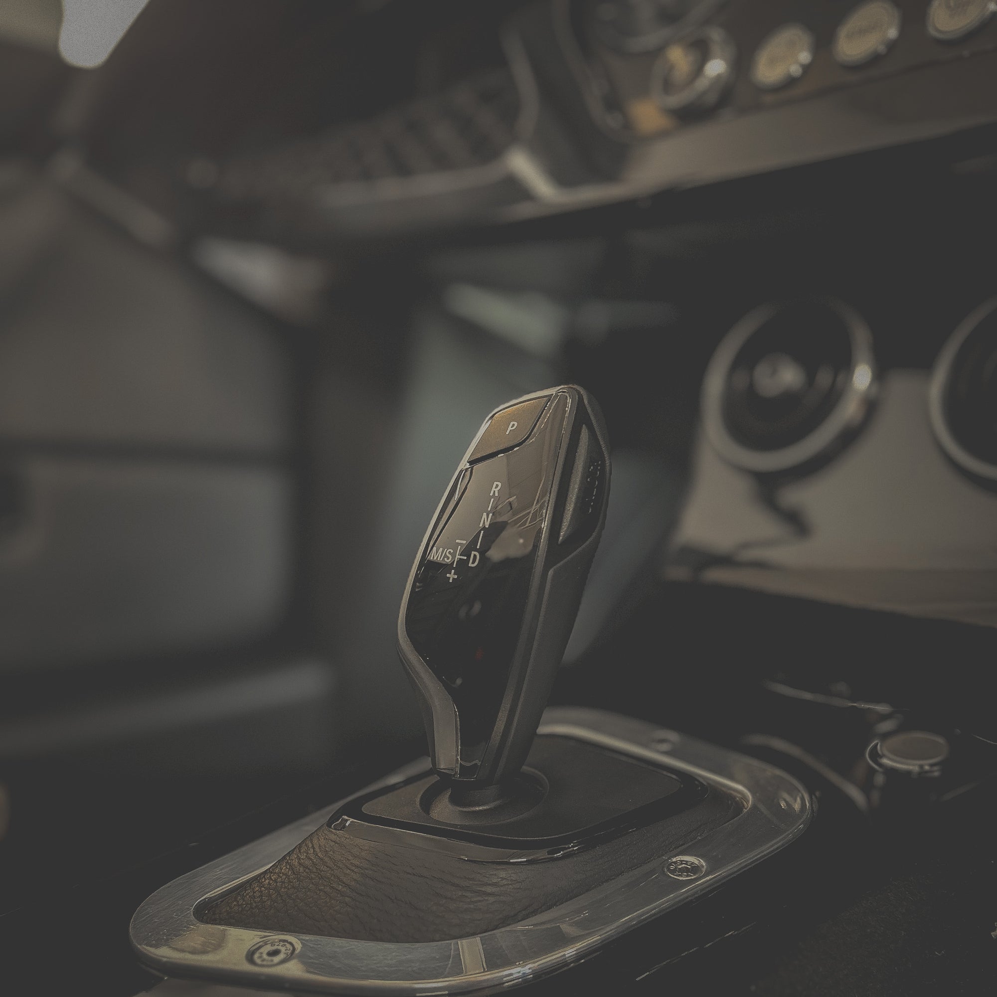 Car gear shift lever with metallic finish in a vehicle interior.