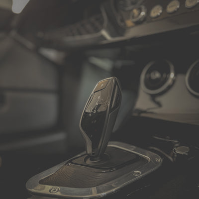 Car gear shift lever with metallic finish in a vehicle interior.