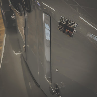 Close-up of a car door with a British flag emblem on a blurred background