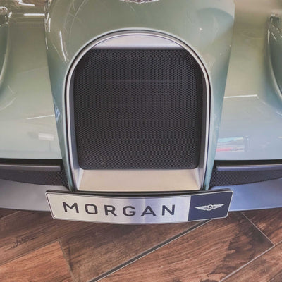 Close-up of a car grille with 'Morgan' branding on a wooden floor.