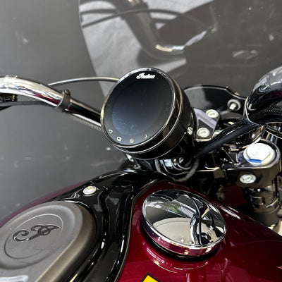 Close-up of motorcycle handlebar with control knob and brand logo.