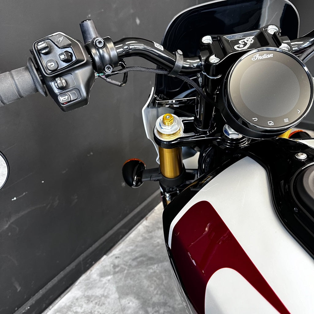 Close-up of a motorcycle handlebar with control buttons and Indian logo.