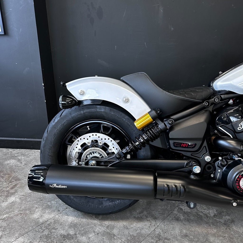 Close-up of a motorcycle's exhaust and wheel against a black background