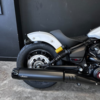 Close-up of a motorcycle's exhaust and wheel against a black background