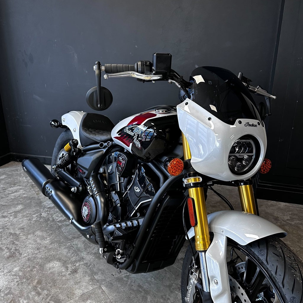 Motorcycle with gold front forks against a dark wall