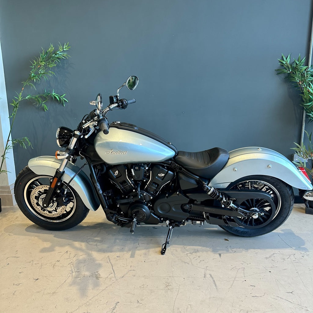Motorcycle parked indoors with a gray wall and plants in the background