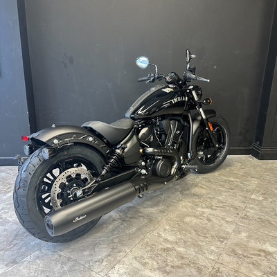 Black motorcycle on a tiled floor with a dark wall background